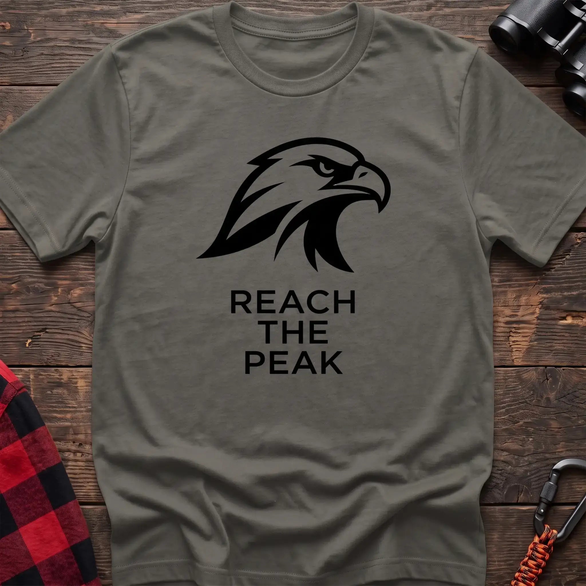 Heather military green crew-neck t-shirt with a black stylized eagle head logo and the text “REACH THE PEAK” printed on the front