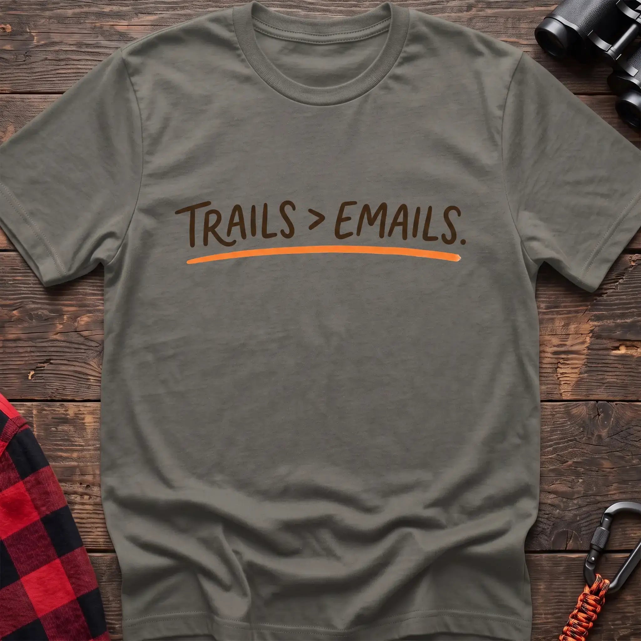 Heather military green t-shirt with brown handwritten-style text reading Trails greater than Emails and an orange underline