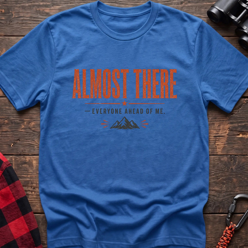 Heather royal cotton t-shirt with a mountain graphic and Almost There Everyone Ahead of Me text on rustic wood