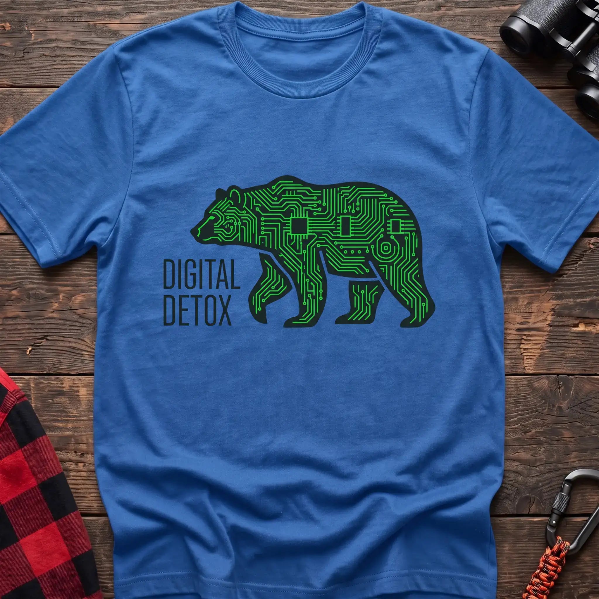 Heather royal t-shirt with a neon green circuit-board patterned silhouette of a walking bear, and the text “DIGITAL DETOX” printed to the left of the design, laid flat on a wooden surface.