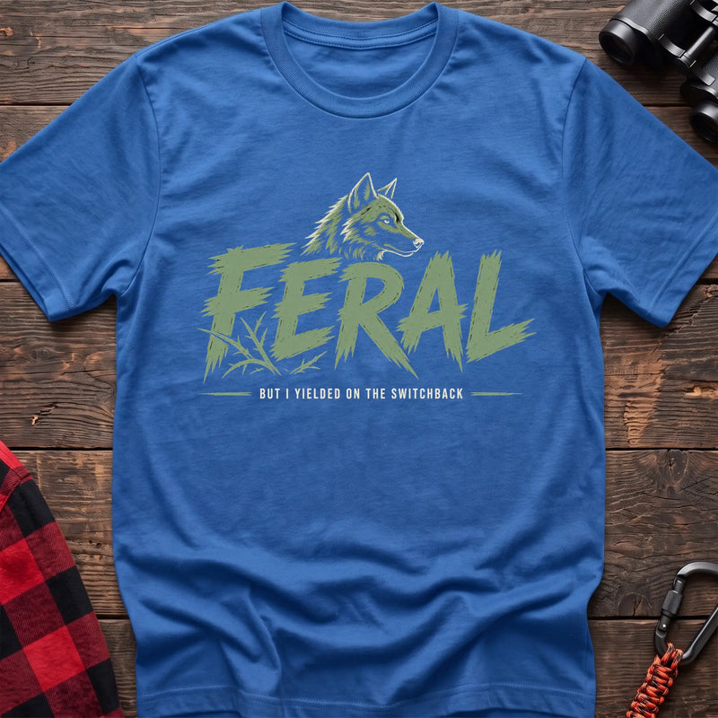 Heather royal cotton t-shirt with a wolf graphic and Feral But I Yielded on the Switchback text on rustic wood