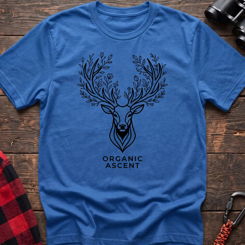 Heather royal t-shirt with a black line drawing of a deer’s head whose antlers are formed from leafy branches and flowers, with the text “ORGANIC ASCENT” printed below, laid flat on a wooden surface.