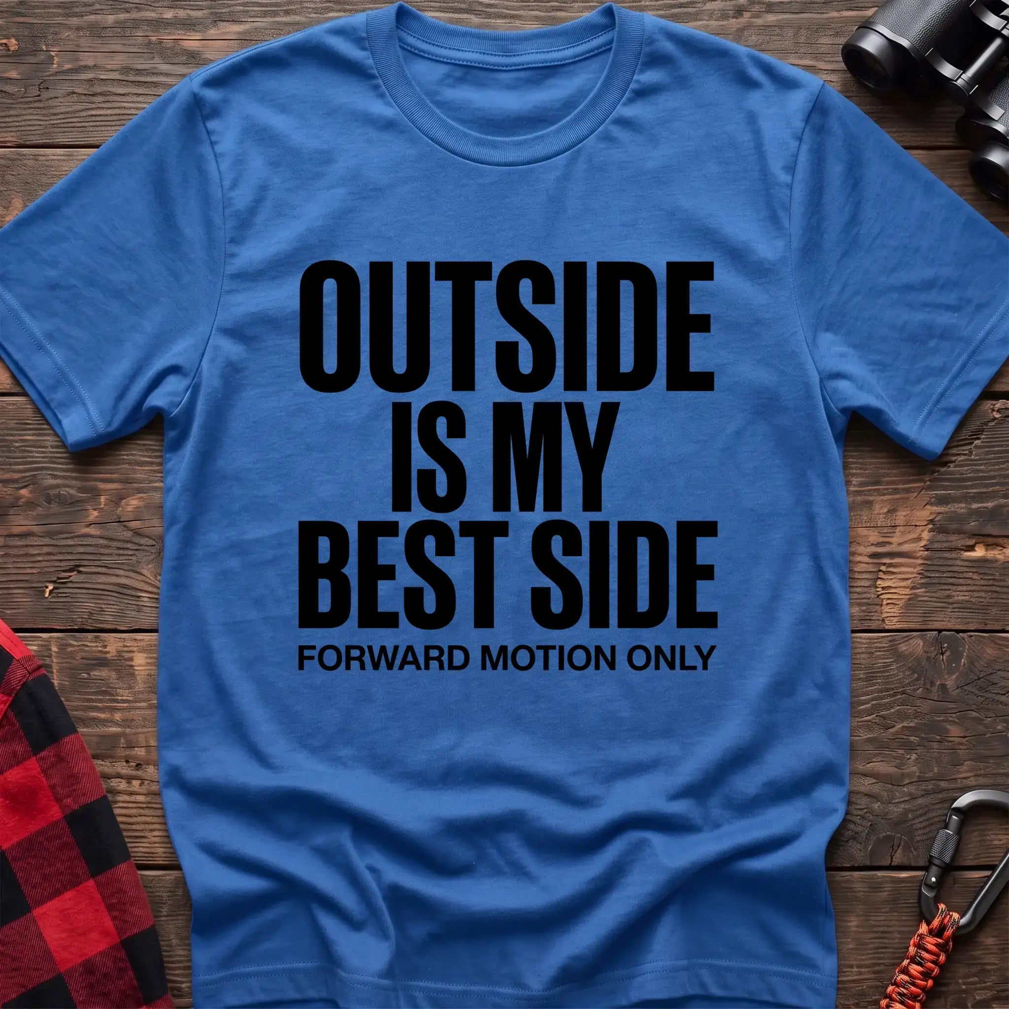 Heather royal t-shirt with bold black text reading “OUTSIDE IS MY BEST SIDE” and “FORWARD MOTION ONLY” below it, laid flat on a wooden surface.