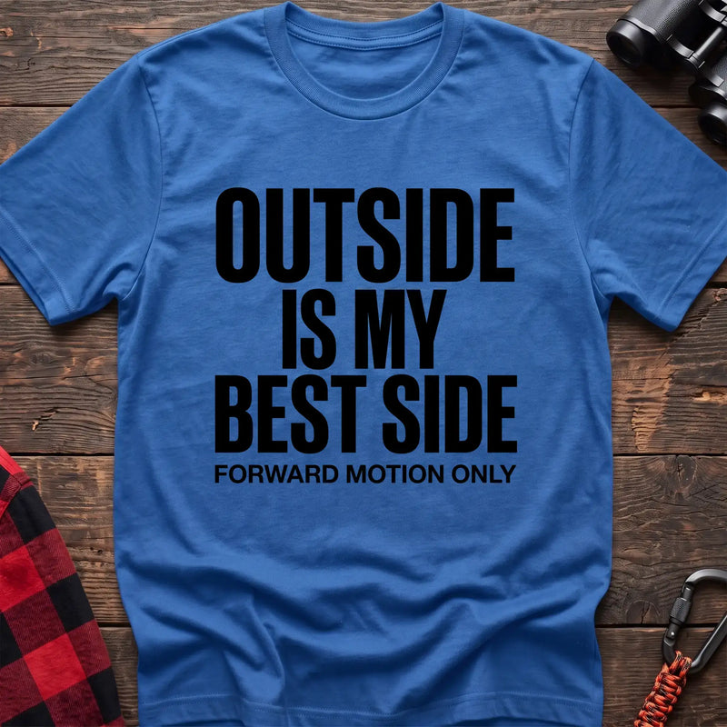 Heather royal t-shirt with bold black text reading “OUTSIDE IS MY BEST SIDE” and “FORWARD MOTION ONLY” below it, laid flat on a wooden surface.