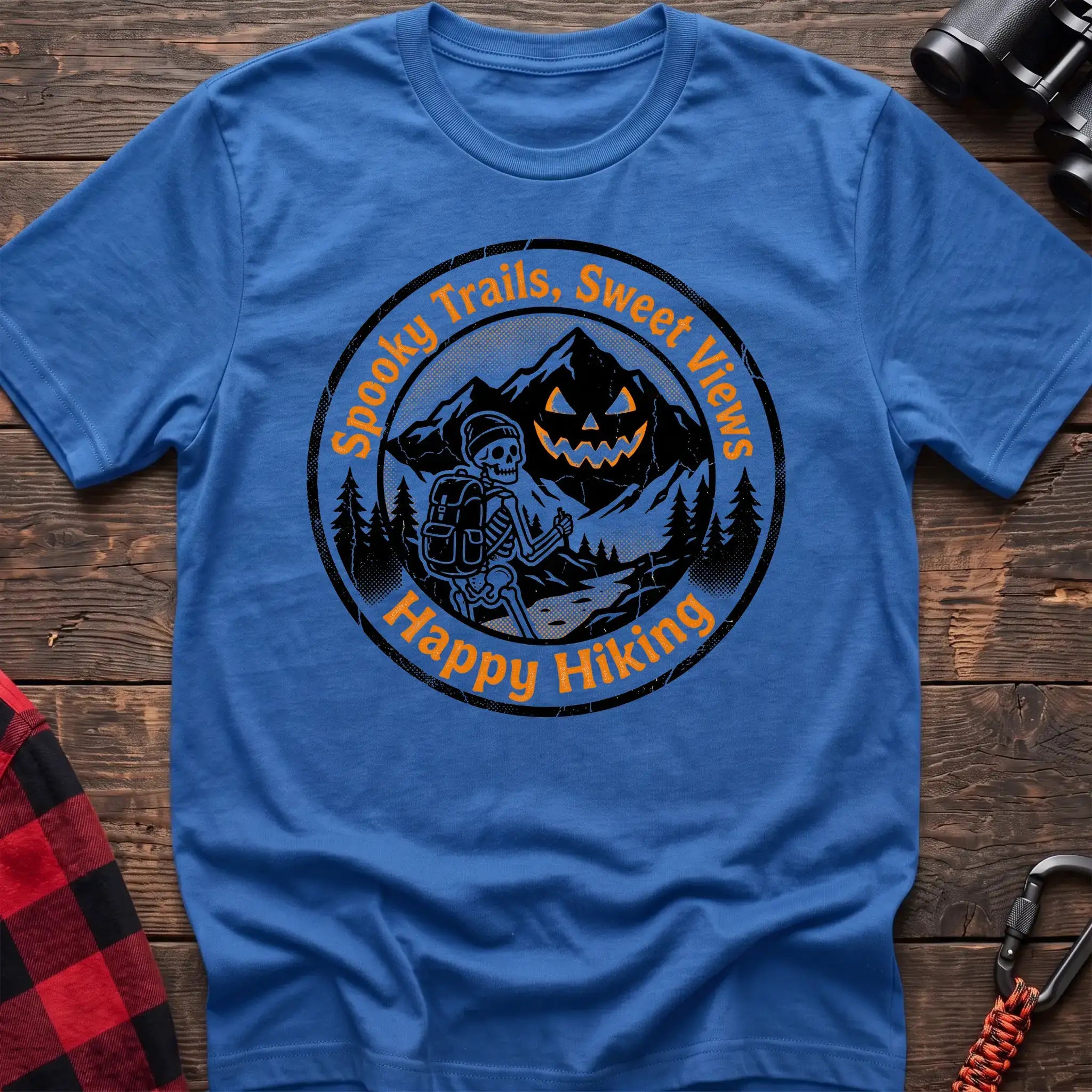 Heather royal t-shirt with circular graphic of a skeleton hiker giving a thumbs up in front of a jack-o-lantern mountain, reading Spooky Trails Sweet Views Happy Hiking