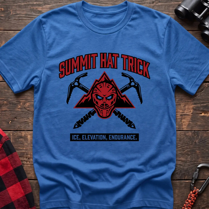Heather royal t-shirt with a red mountain-themed goalie mask and crossed ice axes, with the text “SUMMIT HAT TRICK” and “ICE, ELEVATION, ENDURANCE,” laid flat on a wooden surface.
