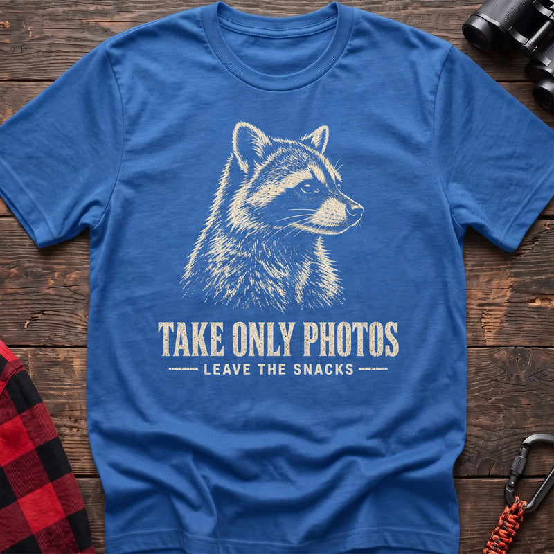 Heather royal cotton t-shirt with a raccoon graphic and Take Only Photos Leave the Snacks text on rustic wood