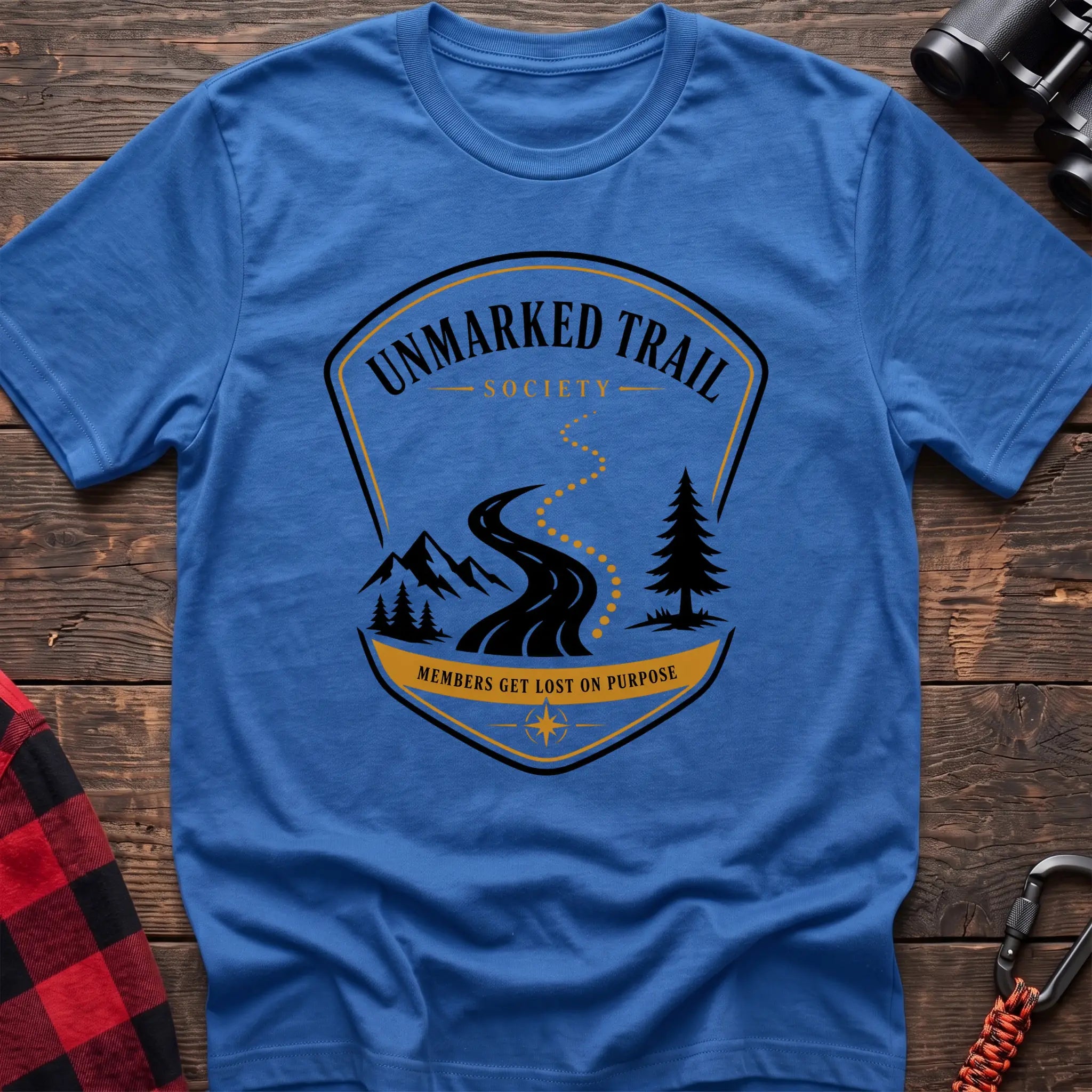 Heather royal cotton hiking t-shirt with Unmarked Trail Society badge, winding trail, mountains, pine trees, and "Members Get Lost on Purpose" text