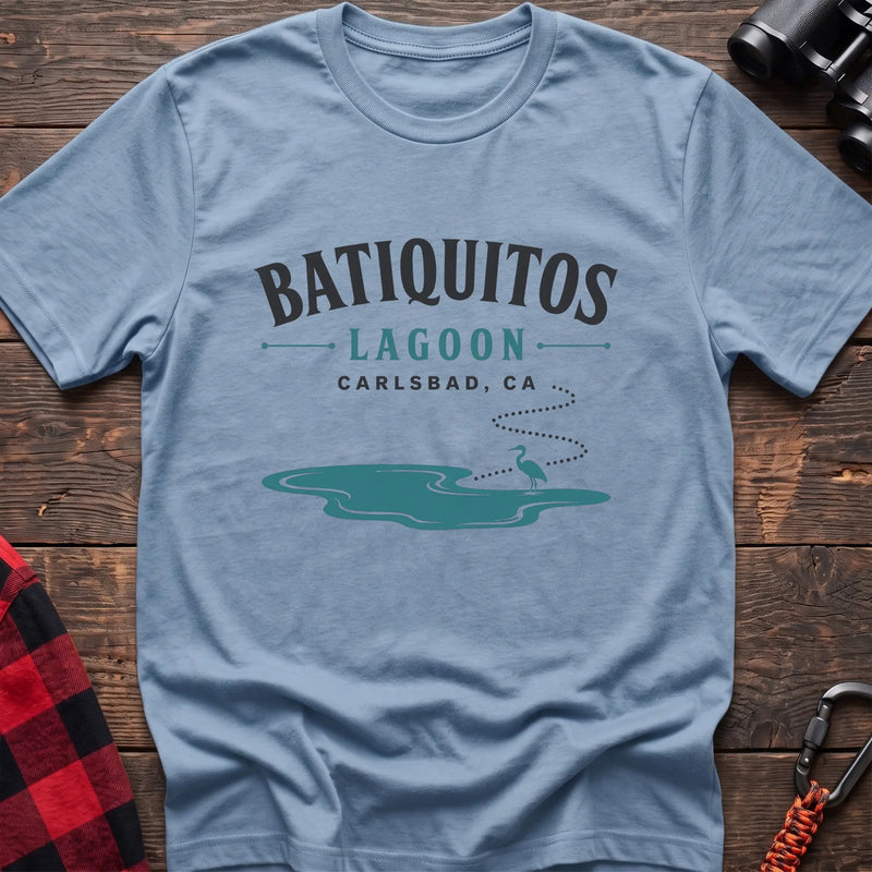 Light blue cotton t-shirt with a heron and lagoon graphic and Batiquitos Lagoon Carlsbad CA text on rustic wood