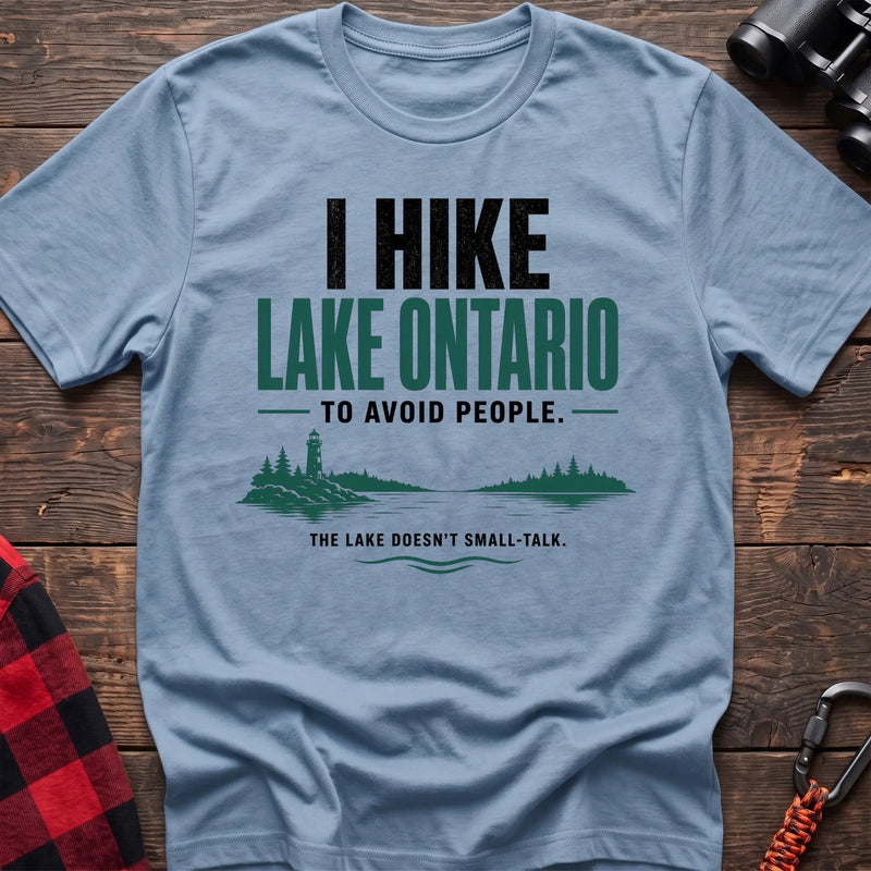 Light blue cotton hiking t-shirt with lighthouse and lake graphic and "I hike Lake Ontario to avoid people – the lake doesn't small-talk" quote