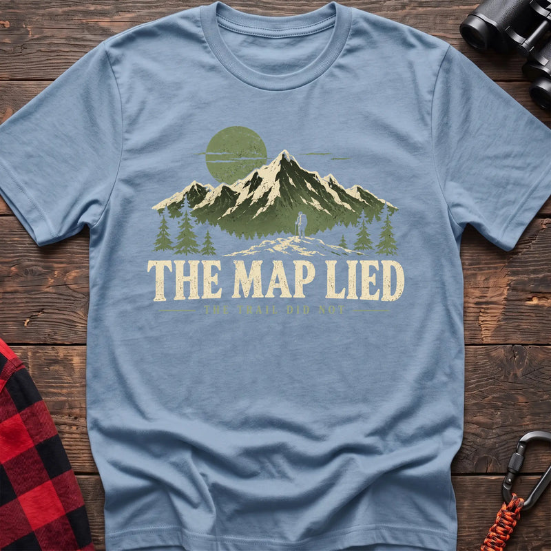 Light blue cotton t-shirt with a hiker and mountain graphic and The Map Lied The Trail Did Not text on rustic wood