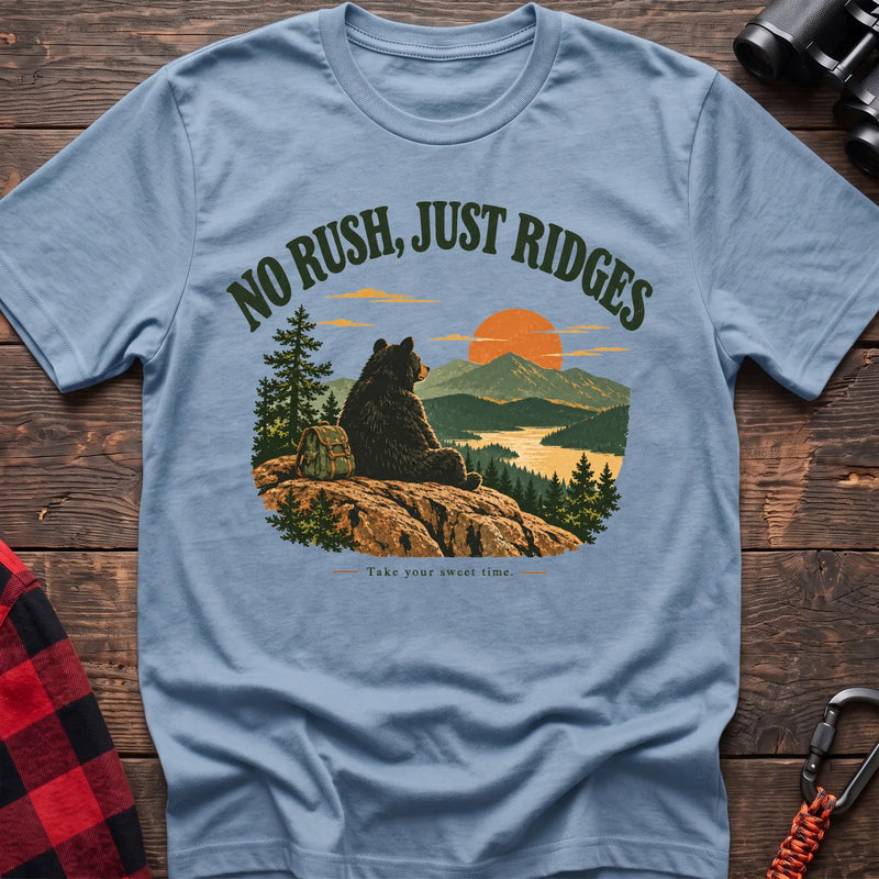 Light blue cotton t-shirt with a bear on a ridge graphic and No Rush Just Ridges text on rustic wood
