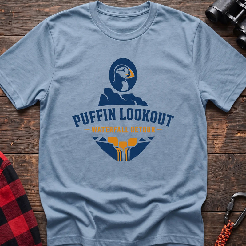 Light blue cotton t-shirt with a puffin and waterfall graphic and Puffin Lookout Waterfall Detour text on rustic wood