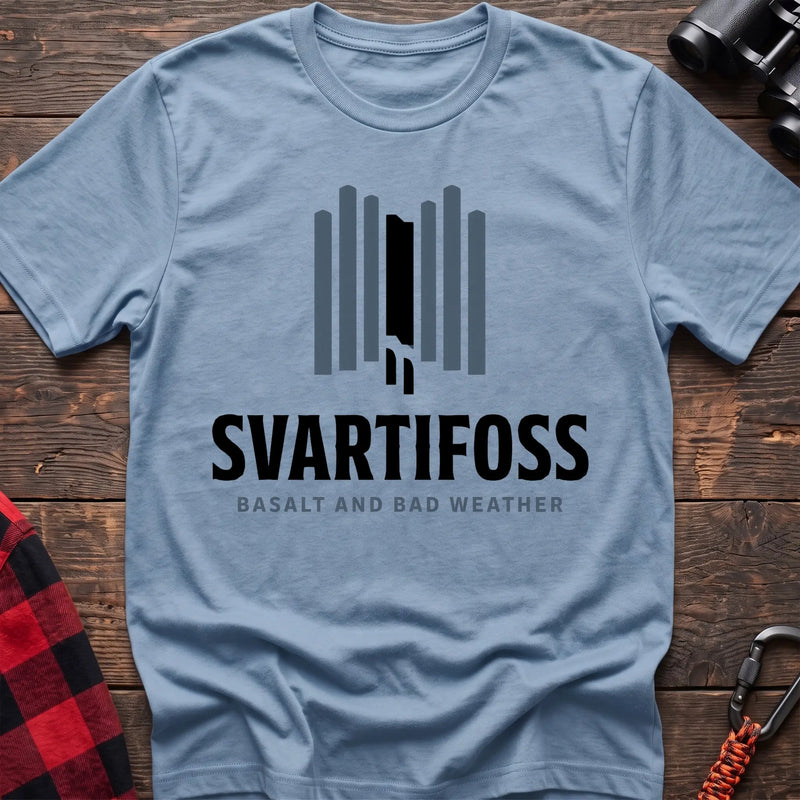 Light blue cotton t-shirt with a basalt column graphic and Svartifoss Basalt and Bad Weather text on rustic wood