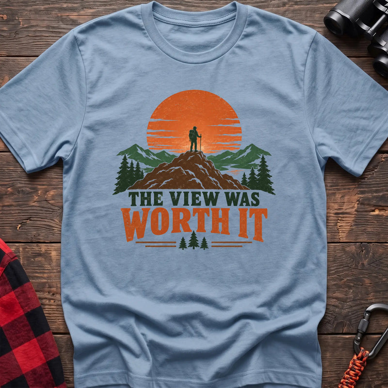 Light blue cotton t-shirt with a hiker on a mountain sunset graphic and The View Was Worth It text on rustic wood