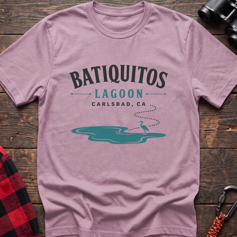 Light pink cotton t-shirt with a heron and lagoon graphic and Batiquitos Lagoon Carlsbad CA text on rustic wood