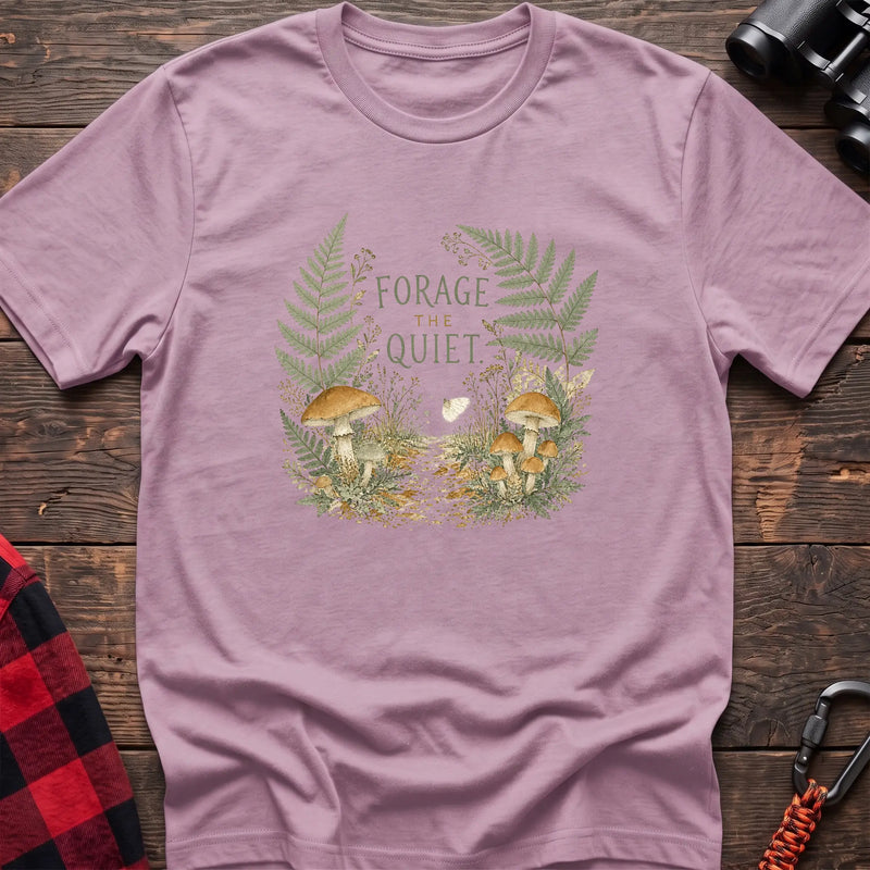 Light pink cotton t-shirt with a mushroom and fern graphic and Forage the Quiet text on rustic wood