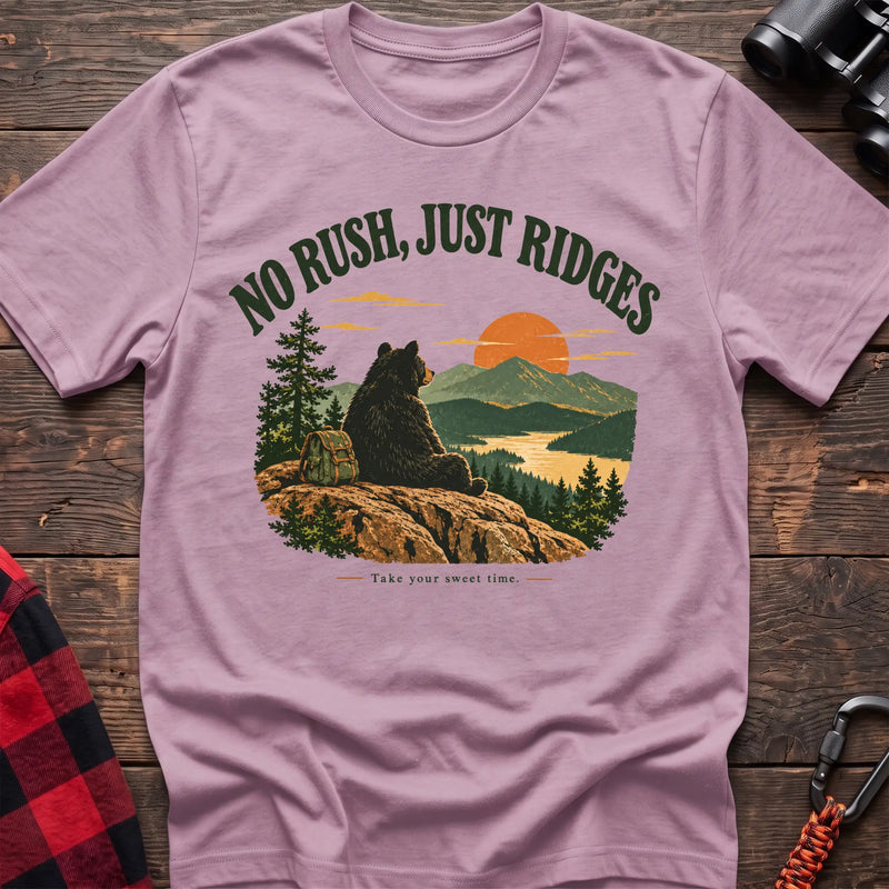Light pink cotton t-shirt with a bear on a ridge graphic and No Rush Just Ridges text on rustic wood