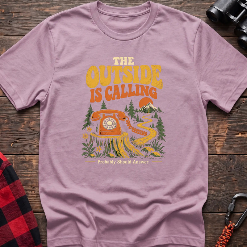 Light pink cotton t-shirt with a rotary phone on a stump graphic and The Outside Is Calling text on rustic wood