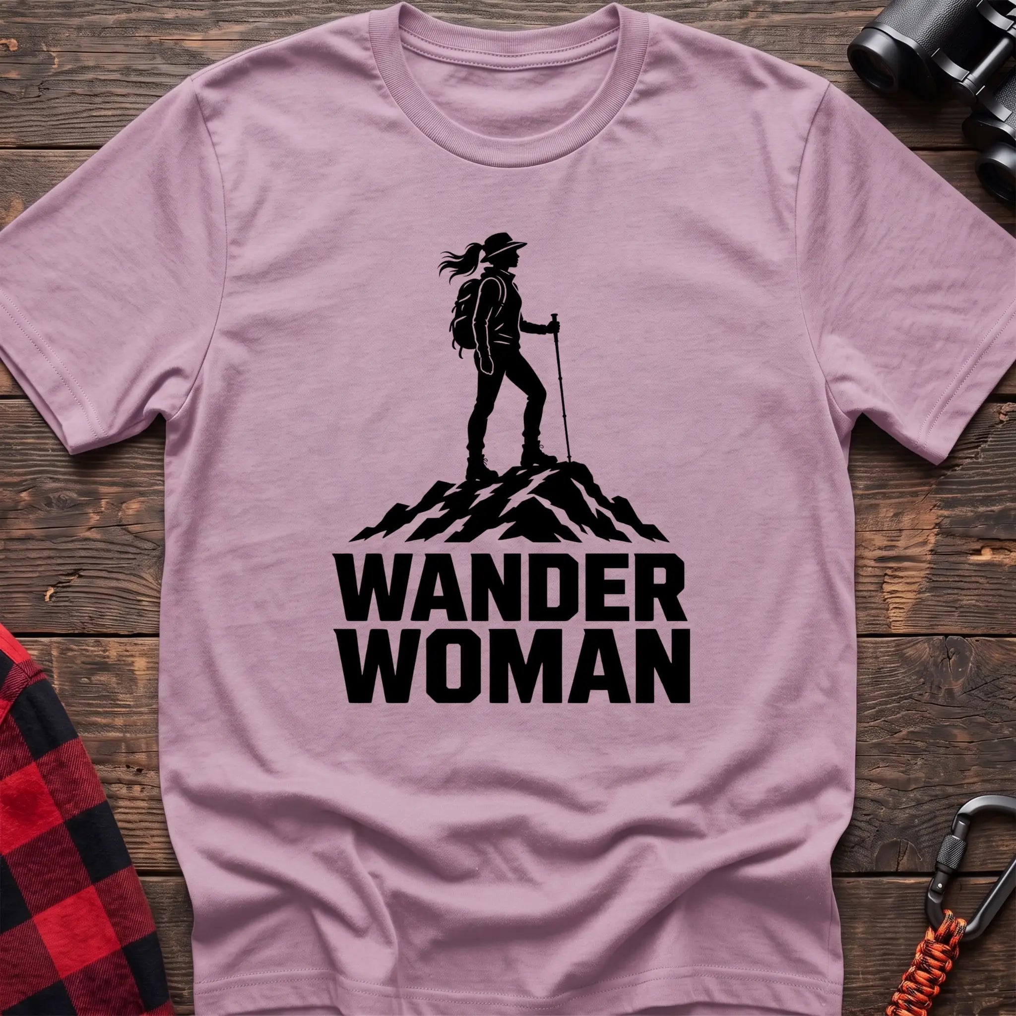 Light pink cotton hiking t-shirt with black silhouette of a female hiker on a mountain peak and bold Wander Woman text