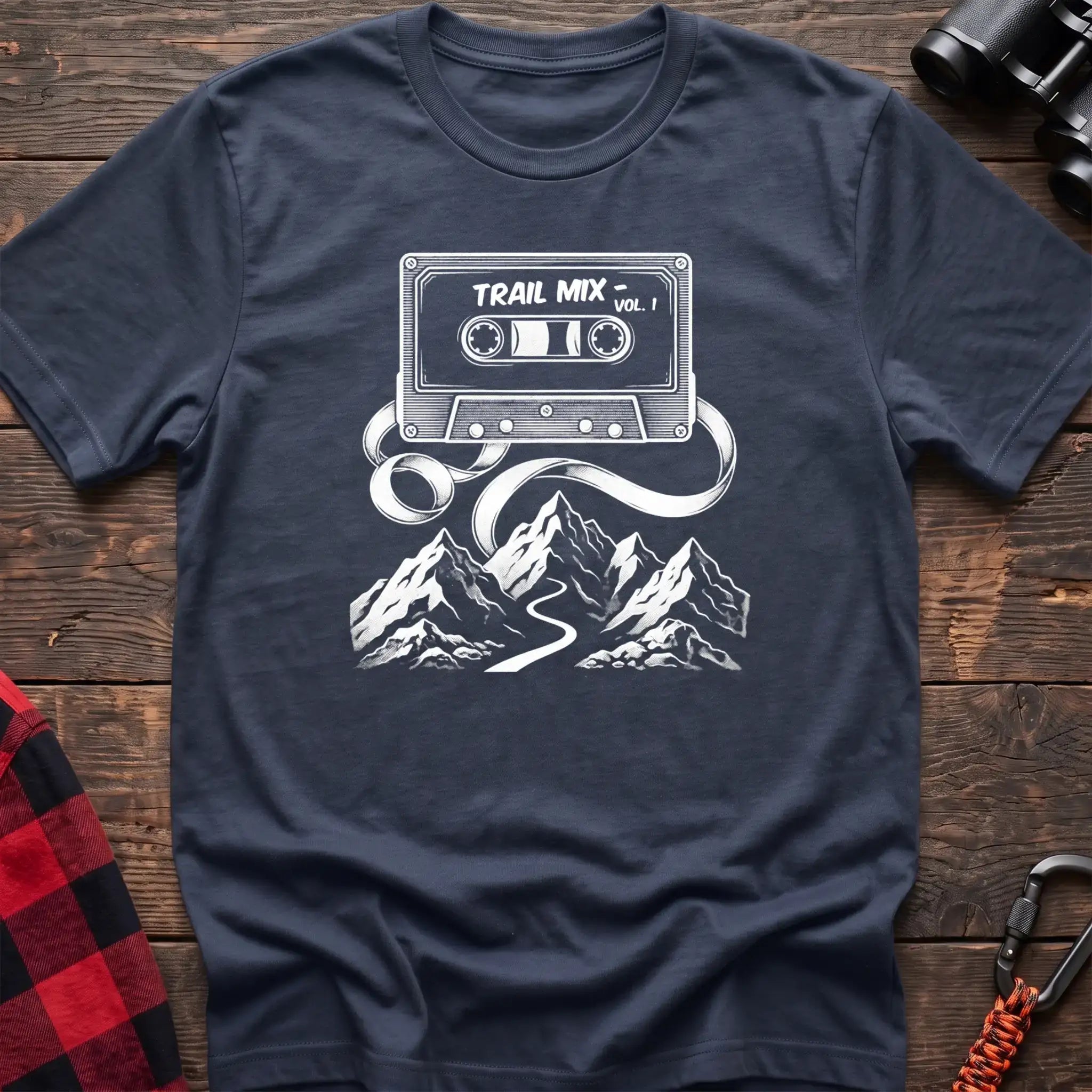 Navy blue t-shirt with white cassette tape graphic labeled Trail Mix Vol. 1, with tape unspooling into a trail through mountains