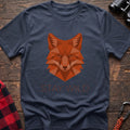 Navy t-shirt with a geometric low-poly orange fox head and the text “STAY WILD” printed below in matching orange, laid flat on a wooden surface.