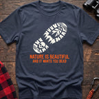 Navy t-shirt with white boot print graphic featuring a skull and pine trees, and orange text reading Nature Is Beautiful And It Wants You Dead