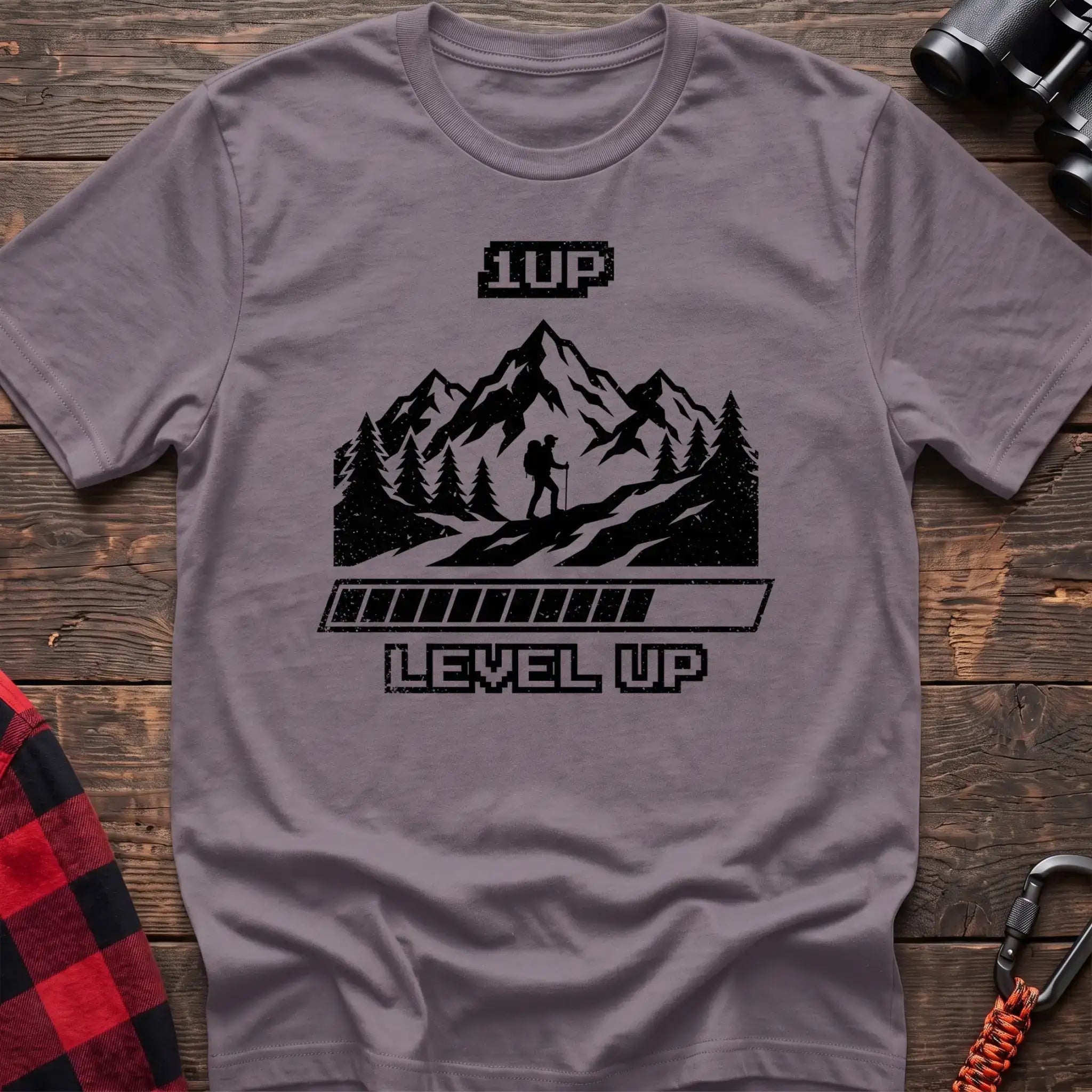 Paragon t-shirt with black graphic of a hiker on a mountain trail under pixel-style 1UP text and a progress bar reading Level Up