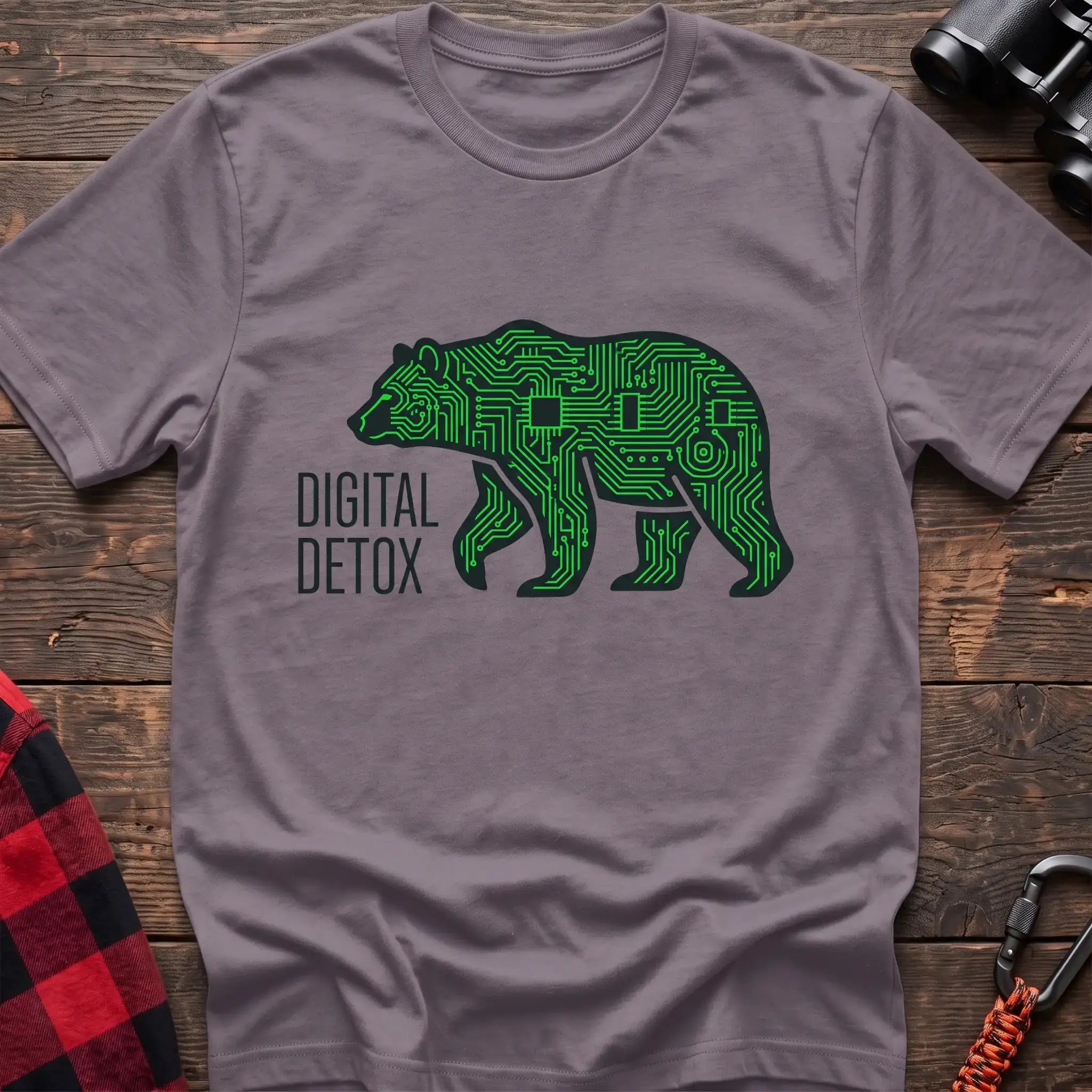 Paragon t-shirt with a neon green circuit-board patterned silhouette of a walking bear, and the text “DIGITAL DETOX” printed to the left of the design, laid flat on a wooden surface.