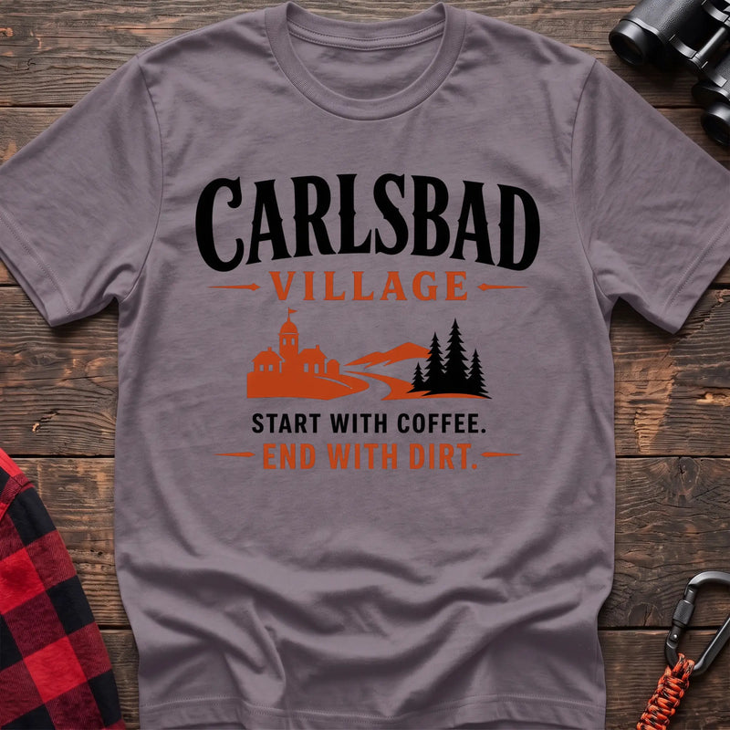 Paragon cotton t-shirt with a village and trail graphic and Carlsbad Village Start with Coffee End with Dirt text on rustic wood