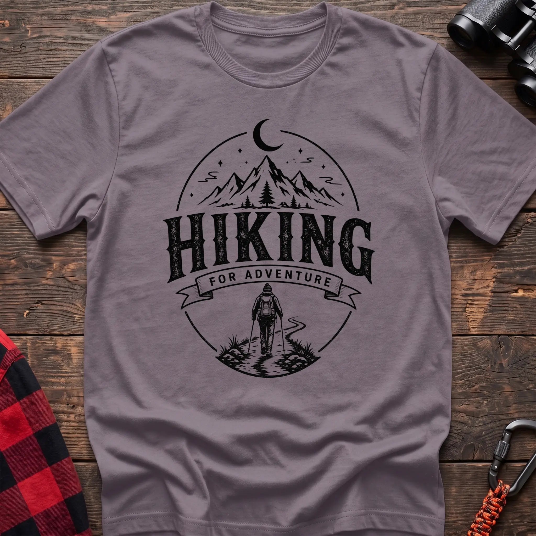 Paragon cotton t-shirt with vintage Hiking for Adventure graphic of mountains under a crescent moon and a hiker on a trail, flat lay on rustic wood with hiking gear