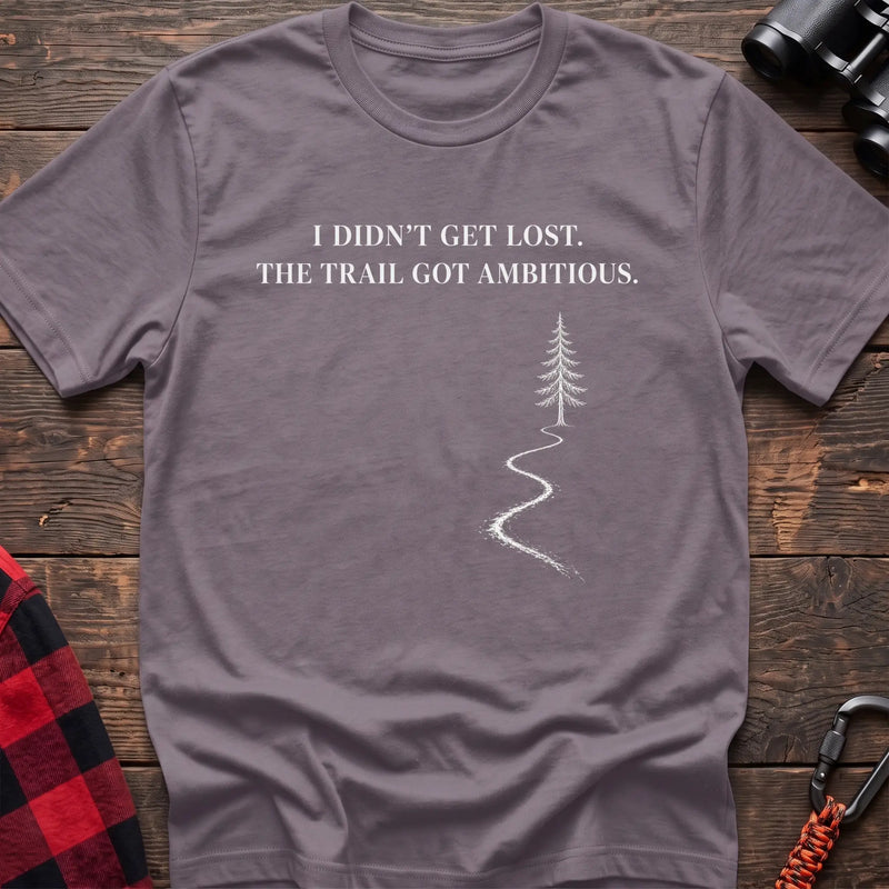 Paragon cotton t-shirt with a winding trail graphic and I Didn’t Get Lost The Trail Got Ambitious text on rustic wood