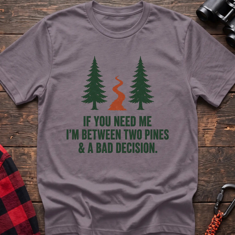 Paragon cotton t-shirt with two pines and a trail graphic and If You Need Me I’m Between Two Pines and a Bad Decision text on rustic wood