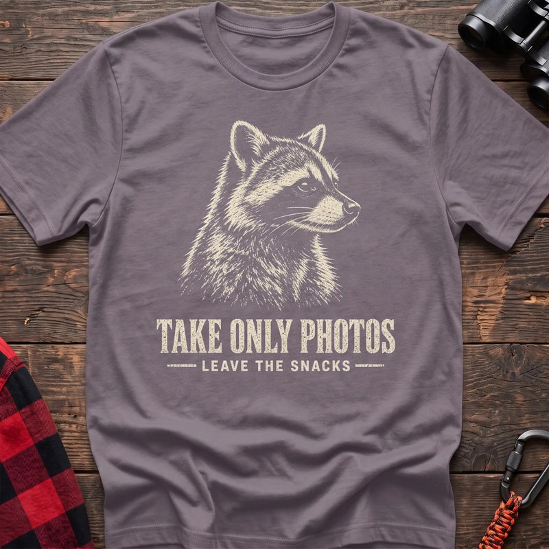 Paragon cotton t-shirt with a raccoon graphic and Take Only Photos Leave the Snacks text on rustic wood
