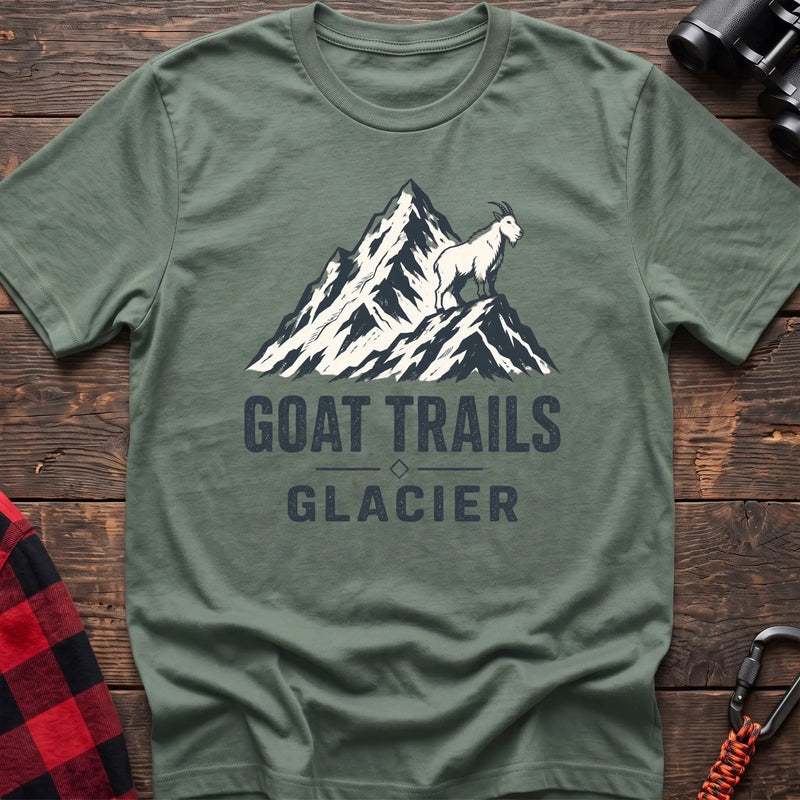 Sage cotton t-shirt with a mountain goat on a peak graphic and Goat Trails Glacier text on rustic wood