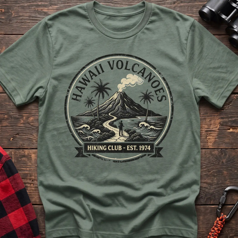 Sage t-shirt with circular Hawaii Volcanoes badge graphic showing a volcano, palm trees, and a hiker, reading Hiking Club Est 1974