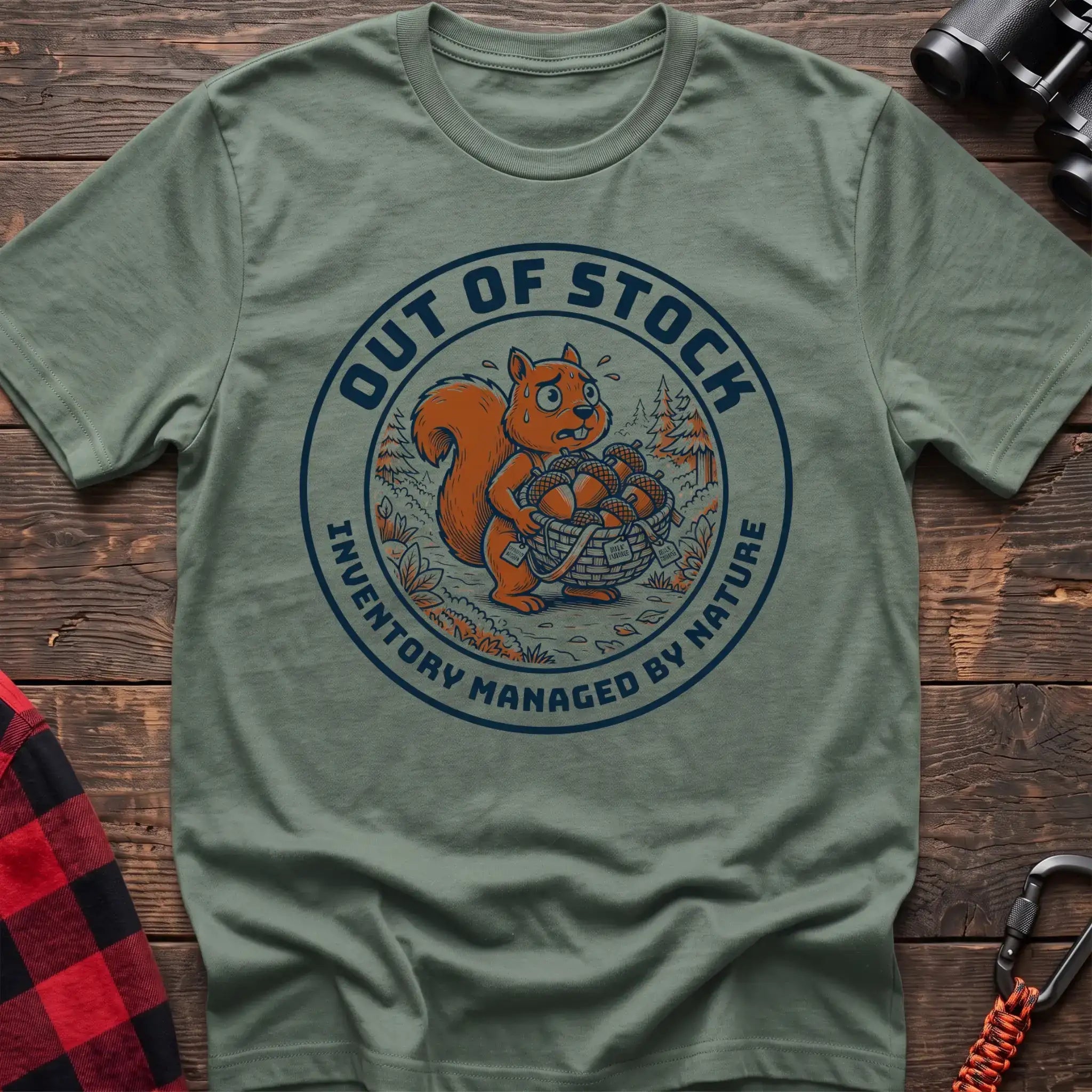 Sage t-shirt with circular graphic of a stressed squirrel holding a basket of acorns, reading Out of Stock Inventory Managed by Nature