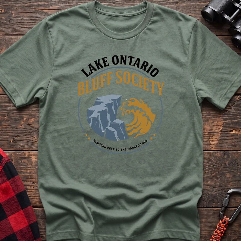 Sage hiking t-shirt with Lake Ontario Bluff Society badge showing a cliff, wave, and Members Keep to the Marked Edge