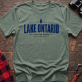 Sage cotton hiking t-shirt with pine tree icon and "Lake Ontario hike the shore" text