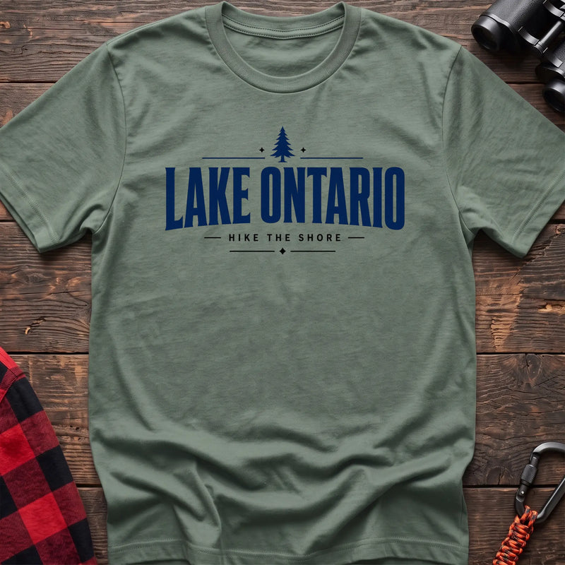 Sage cotton hiking t-shirt with pine tree icon and "Lake Ontario hike the shore" text