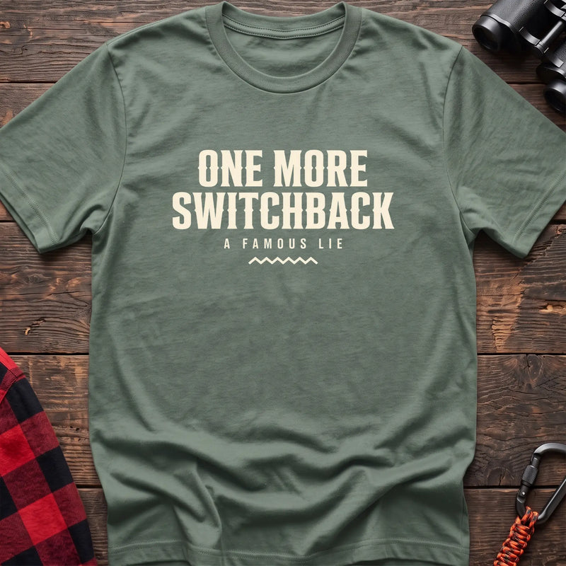 Sage cotton t-shirt with One More Switchback A Famous Lie text on rustic wood