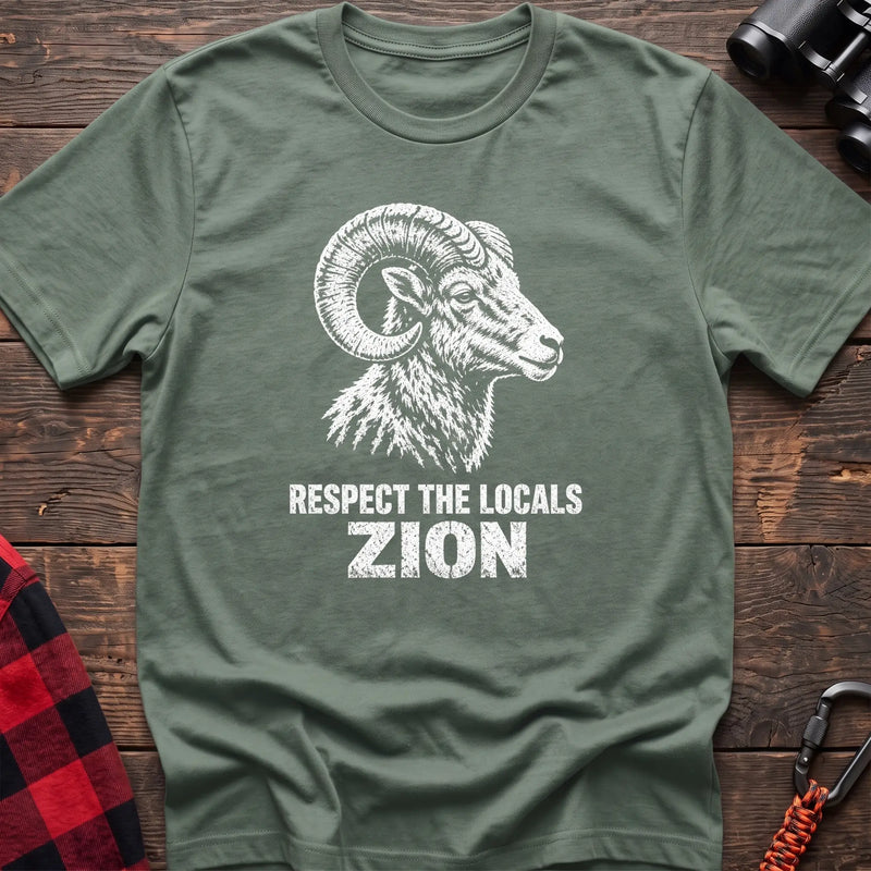 Sage cotton t-shirt with a bighorn ram graphic and Respect the Locals Zion text on rustic wood