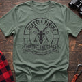 Sage cotton t-shirt with vintage Seattle Hiking graphic of a mountain goat in a circular badge, Protect the Trails Washington Wildlife Division design, flat lay on rustic wood with hiking gear