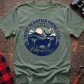 Sage green t-shirt with circular badge graphic of a deer in the mountains reading Smoky Mountain Hiking Club Tennessee