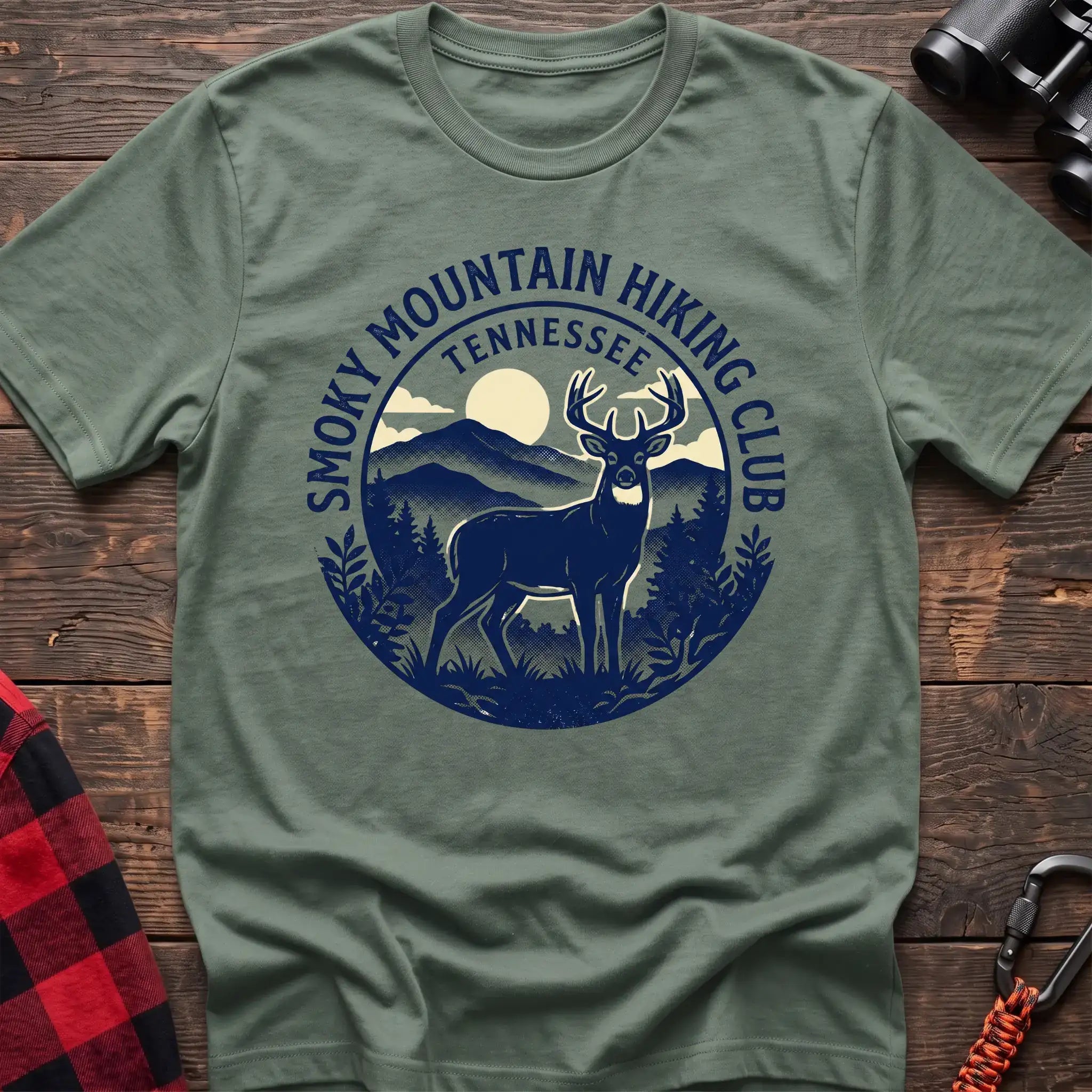 Sage green t-shirt with circular badge graphic of a deer in the mountains reading Smoky Mountain Hiking Club Tennessee