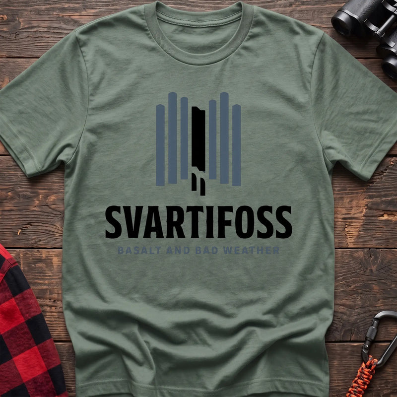 Sage cotton t-shirt with a basalt column graphic and Svartifoss Basalt and Bad Weather text on rustic wood