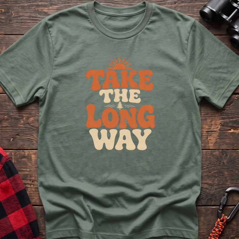 Sage cotton t-shirt with retro wavy text and Take the Long Way lettering on rustic wood