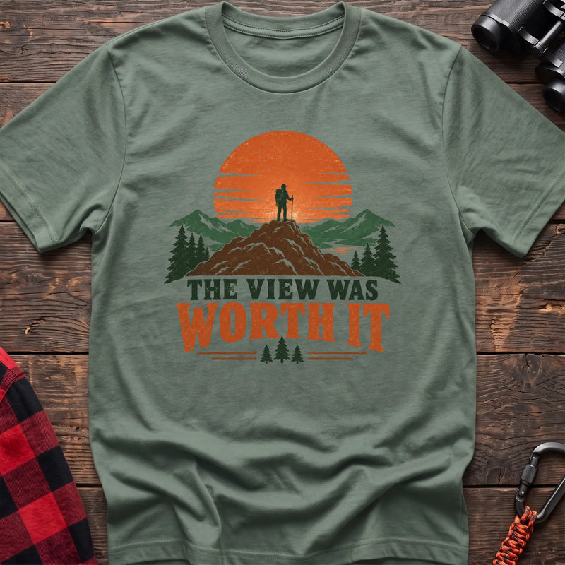 Sage cotton t-shirt with a hiker on a mountain sunset graphic and The View Was Worth It text on rustic wood