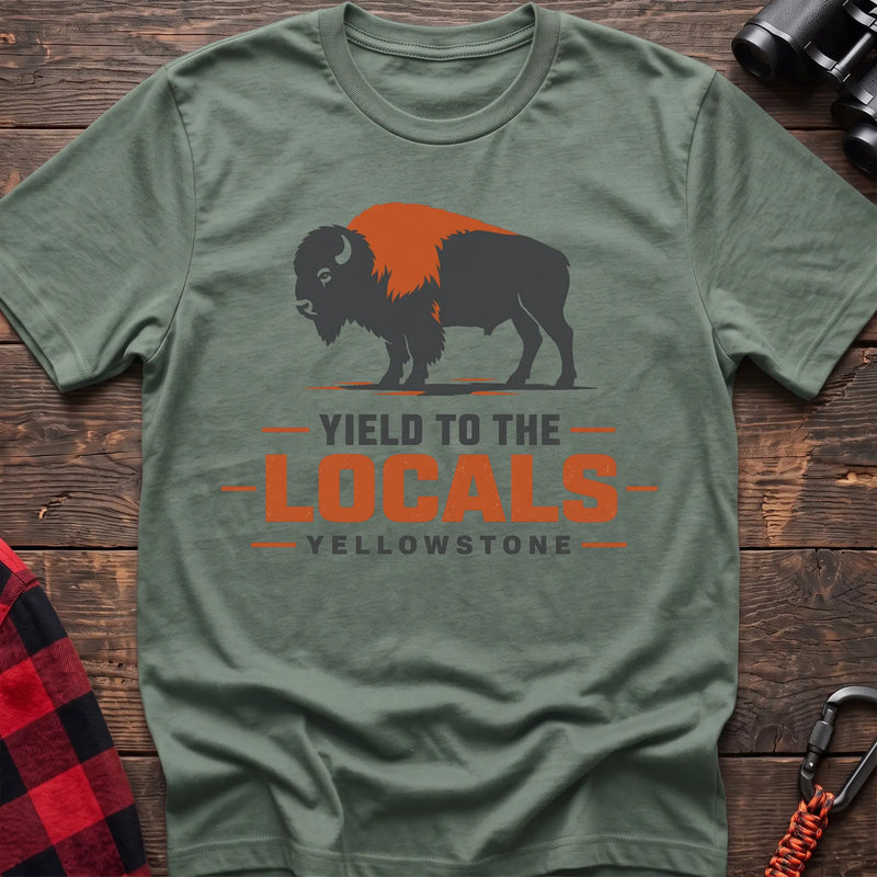 Sage cotton t-shirt with a bison graphic and Yield to the Locals Yellowstone text on rustic wood