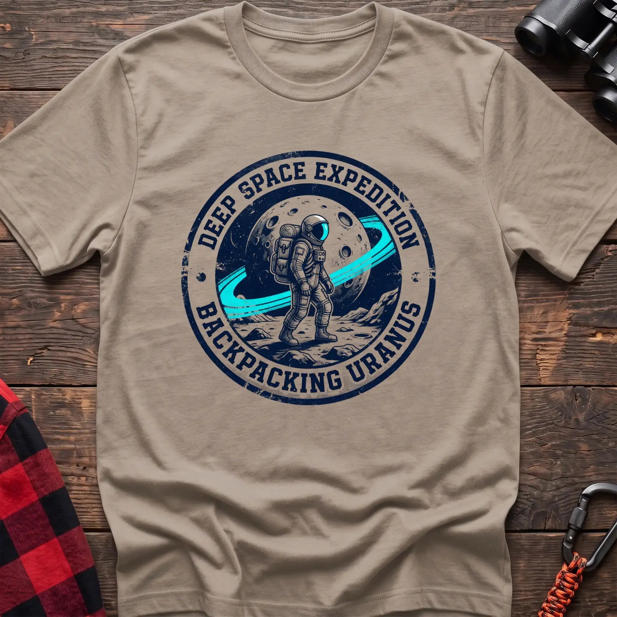 Sand t-shirt with circular badge graphic of an astronaut backpacking on Uranus, reading Deep Space Expedition Backpacking Uranus